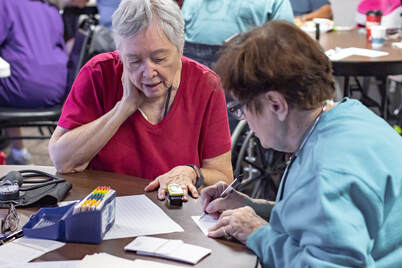Female volunteer helping older woman with tablet